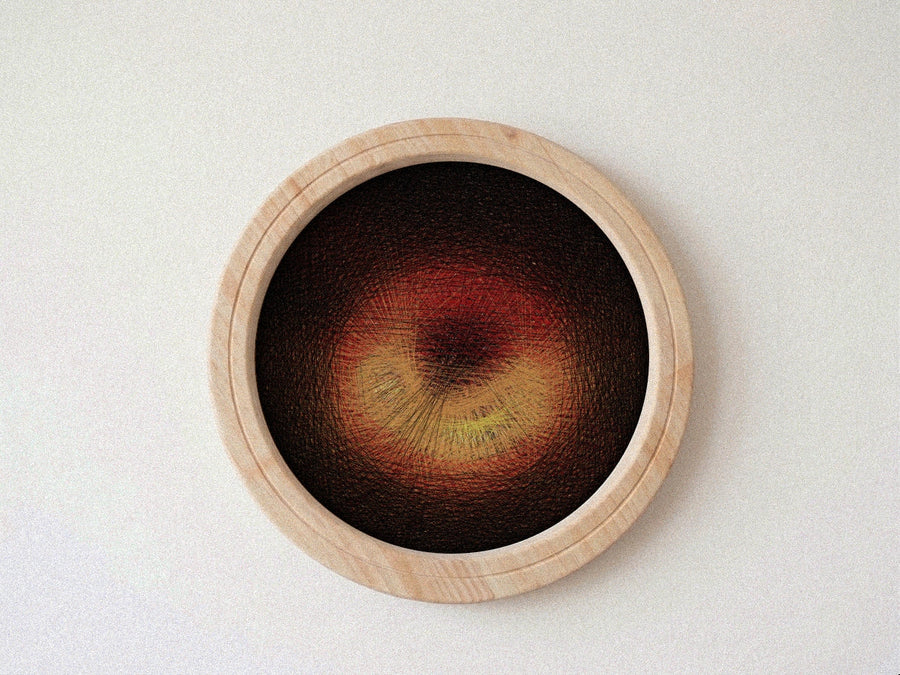 A circular wooden-framed string art piece featuring a textured abstract design in deep brown, red, and yellow tones, mounted on a light off-white textured wall.