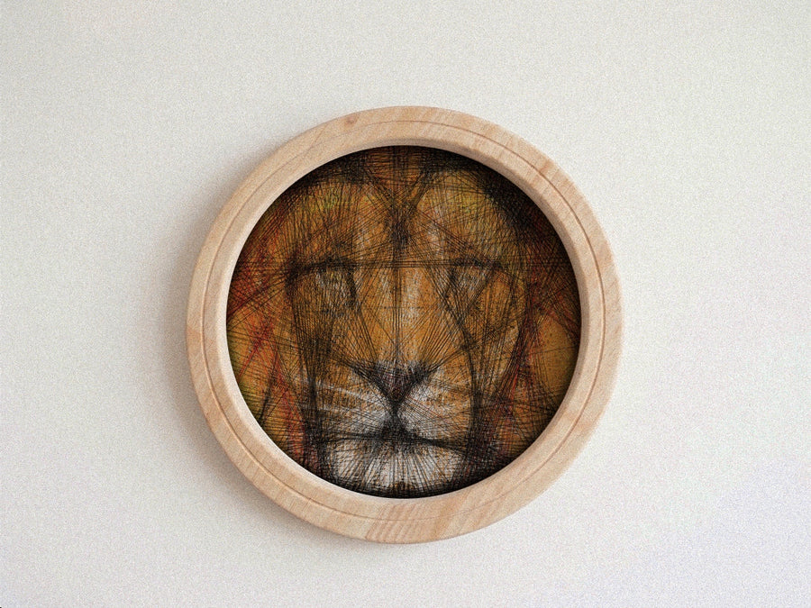 A circular wooden framed string art piece featuring a lion face created with dense black string over a warm brown and orange background, mounted on a light textured wall.
