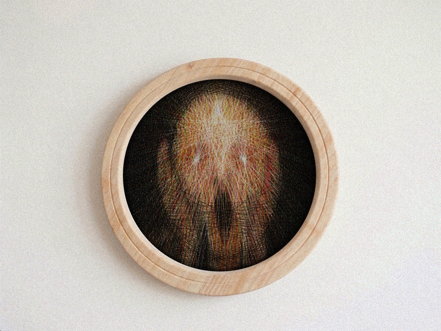A circular framed string art piece featuring a highly detailed, needlepoint skull design in shades of brown, beige, and black, set within a light natural wood frame against a neutral off-white background.