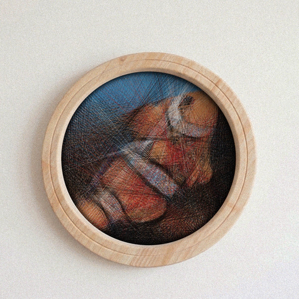 A circular wooden-framed string art featuring a colorful abstract or painted scene with a blue background and warm orange, red, and brown tones, mounted against a plain light wall.