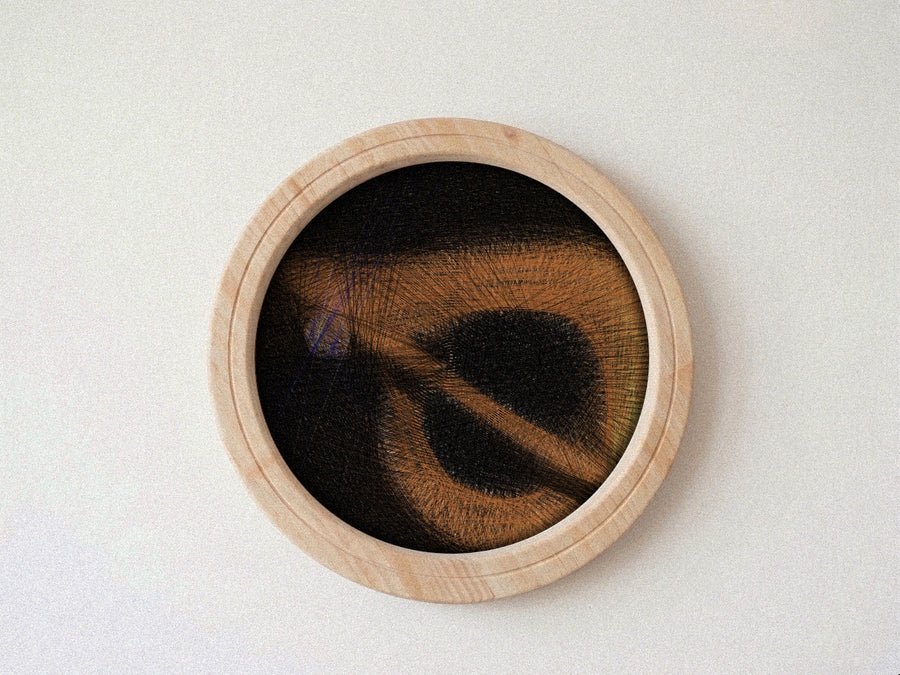 A circular wooden-framed string art artwork featuring a dark abstract design with warm brown and tan textured lines, mounted against a plain off-white wall.