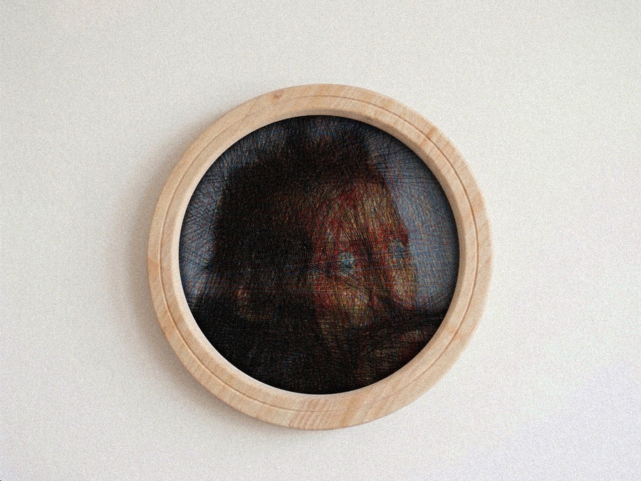 A circular wall string piece featuring a portrait of a woman's face created with thread over a dark mesh background, framed in a light natural wood border, mounted on a plain off-white wall.